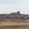 Vista de Cerecinos de Campos con la torre de la iglesia sobre los tejados y campos secos delante