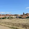 Vista general de Prado, con sus casas y la torre de la iglesia tras un campo de hierba seca