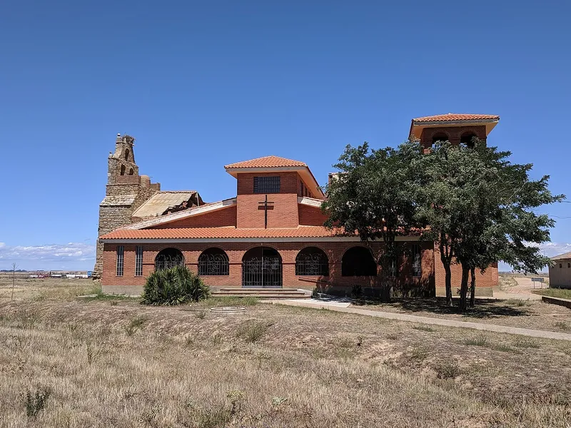 Iglesia nueva de ladrillo junto a la torre en ruinas de la antigua iglesia de Quintanilla del Monte