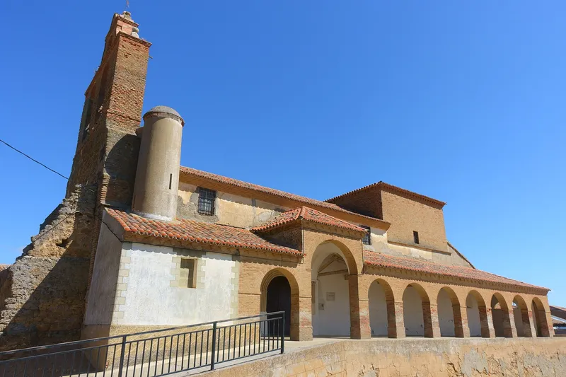Iglesia de San Babilés de Quintanilla del Olmo con torre de ladrillo y pórtico de arcos