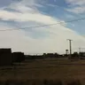 Afueras de San Esteban del Molar con casetas de adobe y depósito de agua bajo un cielo con nubes altas