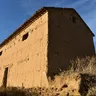 Construcción tradicional de adobe con tejado de teja en Vidayanes, bajo un cielo azul