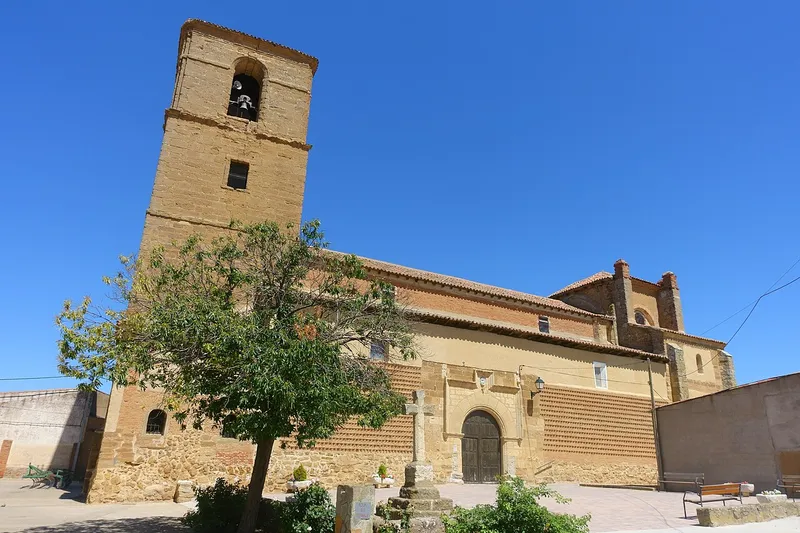 Torre de piedra de la iglesia de la Asunción de Villamayor de Campos tras un árbol