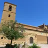 Torre de piedra de la iglesia de la Asunción de Villamayor de Campos tras un árbol
